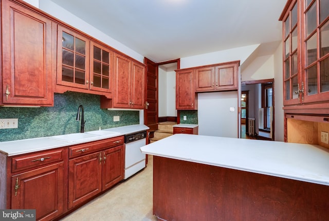 kitchen with white dishwasher, a sink, backsplash, light countertops, and glass insert cabinets