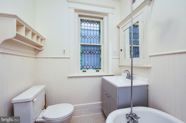 bathroom featuring a wainscoted wall, toilet, vanity, tile patterned floors, and wood walls