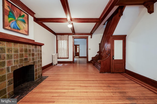 unfurnished living room with radiator, light wood-style flooring, baseboards, beamed ceiling, and coffered ceiling