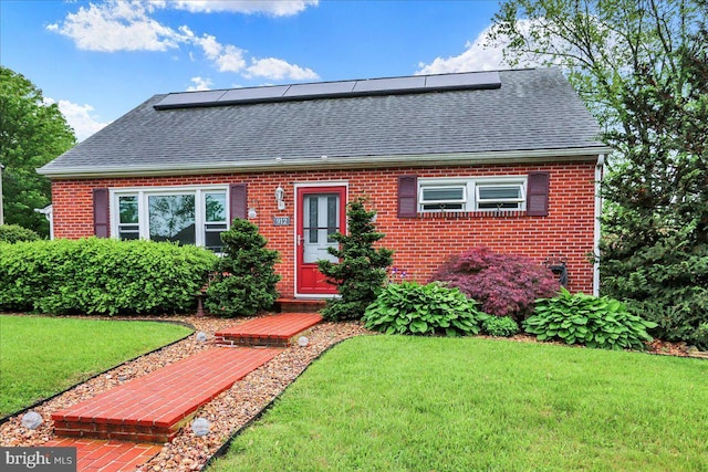 view of front of home featuring roof with shingles, brick siding, and a front lawn