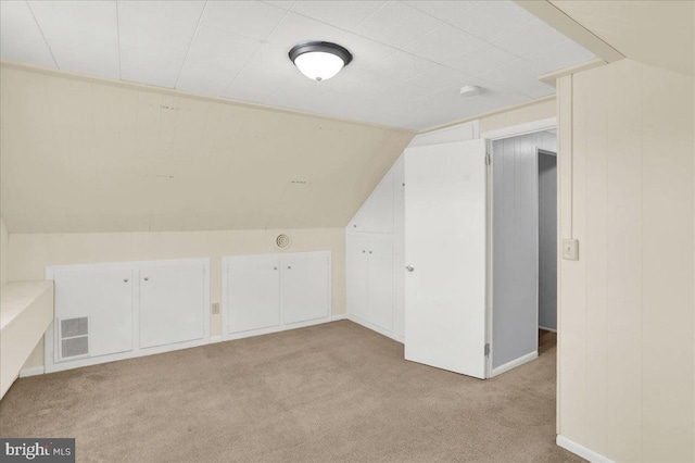 additional living space featuring light carpet, vaulted ceiling, and baseboards