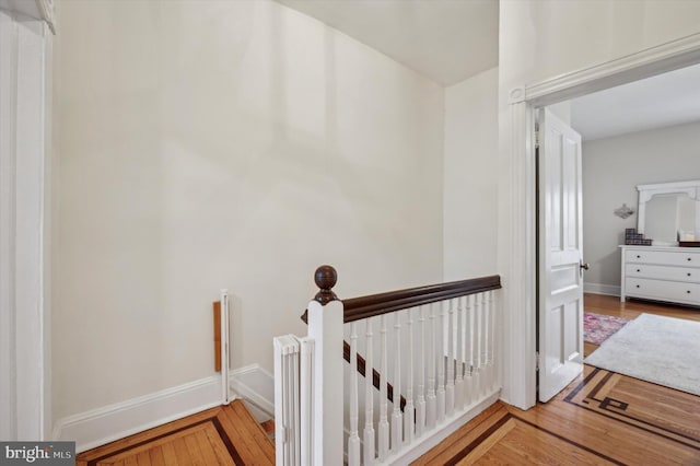 corridor featuring an upstairs landing, wood finished floors, and baseboards