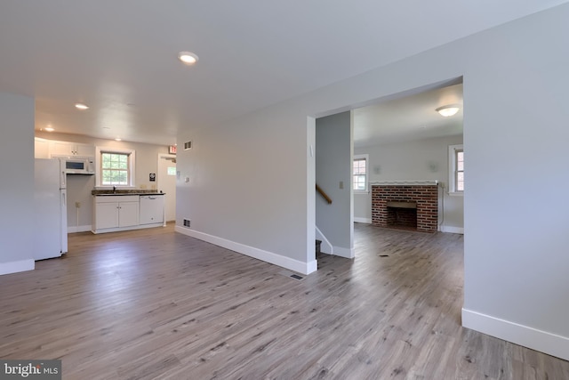 unfurnished living room with baseboards, stairs, light wood finished floors, and recessed lighting