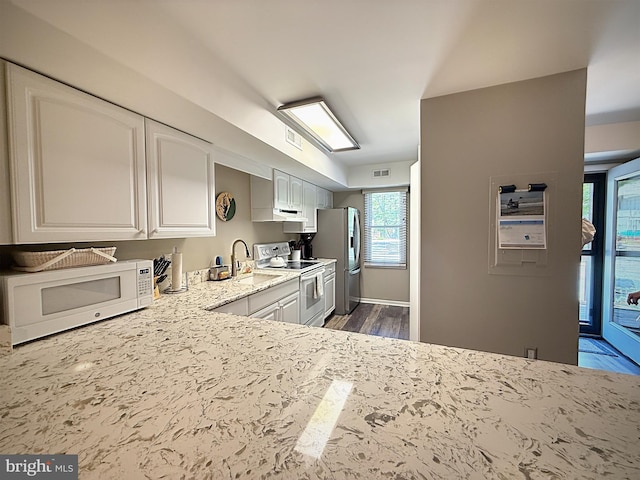 435 Lekites Ave Unit 435, Bethany Beach, DE 19930 - kitchen featuring white appliances, a sink, white cabinetry, dark wood-style flooring, and light stone countertops