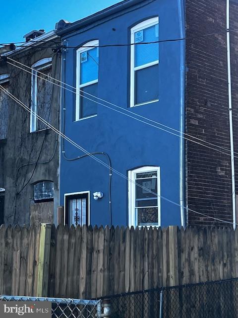 view of side of home featuring fence and stucco siding