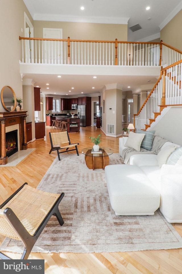 710 Crisfield Way, Annapolis, MD 21401 - living area with crown molding, a high ceiling, light wood-style floors, stairway, and a warm lit fireplace