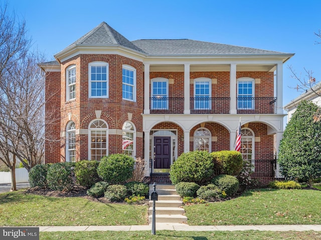 710 Crisfield Way, Annapolis, MD 21401 - view of front facade with a balcony, brick siding, a front yard, a porch, and roof with shingles