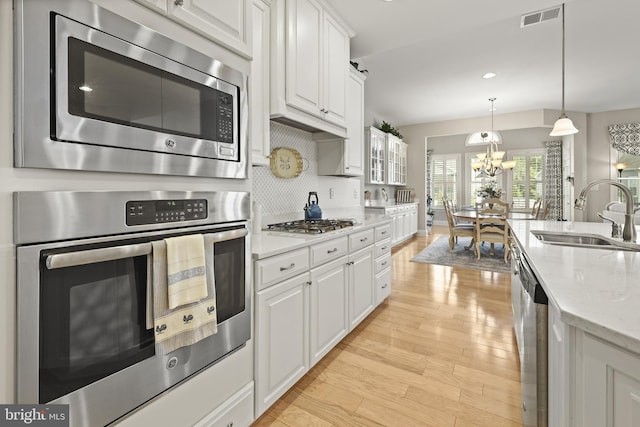 37546 Bella Via Way, Ocean View, DE 19970 - kitchen with a sink, stainless steel appliances, white cabinets, light wood-style flooring, and a chandelier
