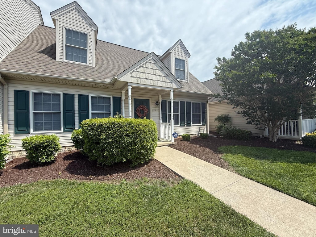 new england style home featuring a front lawn and a shingled roof
