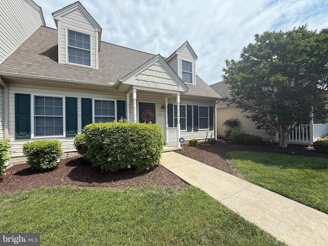 new england style home featuring a front lawn and a shingled roof