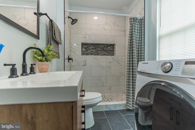 full bathroom with washer / dryer, toilet, vanity, and a tile shower