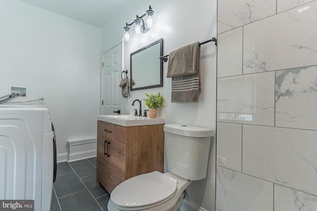 bathroom featuring washer / dryer, toilet, vanity, tile patterned floors, and baseboards