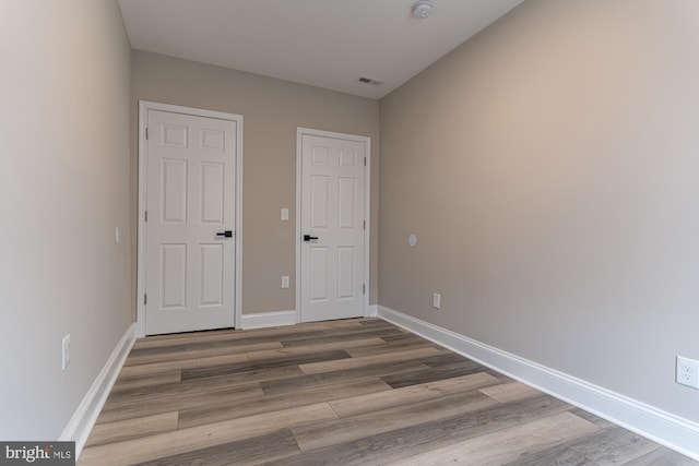 unfurnished bedroom featuring wood finished floors and baseboards