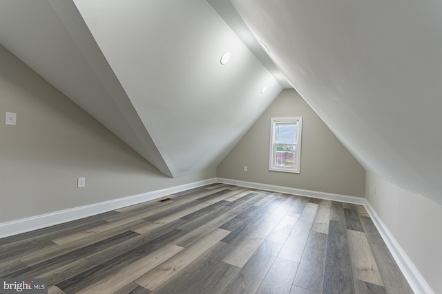 bonus room featuring lofted ceiling, dark wood-style flooring, and baseboards