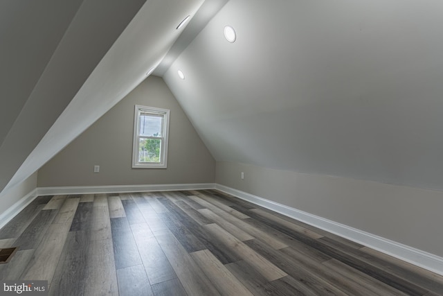 additional living space featuring dark wood-type flooring, baseboards, and vaulted ceiling