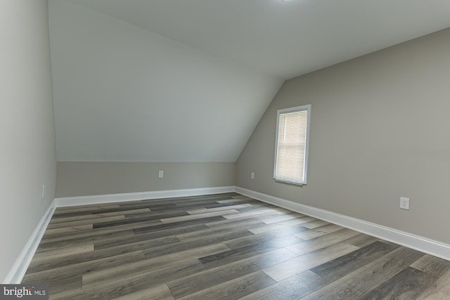 bonus room with dark wood-type flooring, vaulted ceiling, and baseboards