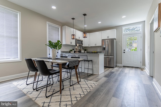 dining room with recessed lighting, baseboards, and light wood-type flooring