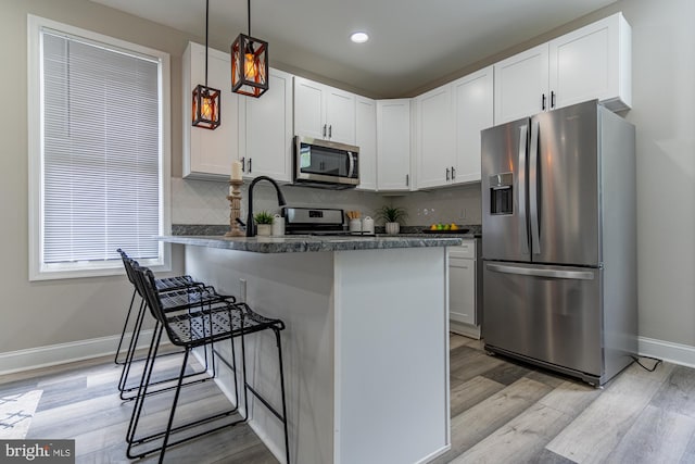 kitchen with stainless steel appliances, light wood finished floors, white cabinetry, baseboards, and recessed lighting