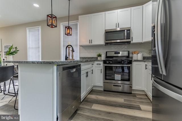 kitchen with stainless steel appliances, a peninsula, backsplash, white cabinets, and recessed lighting