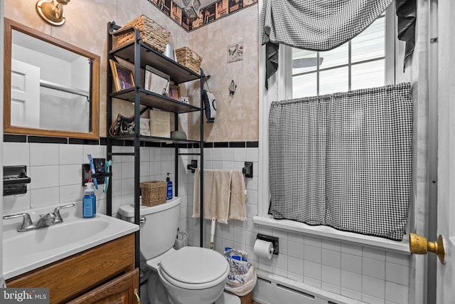 full bath with tile walls, toilet, vanity, a wainscoted wall, and wallpapered walls
