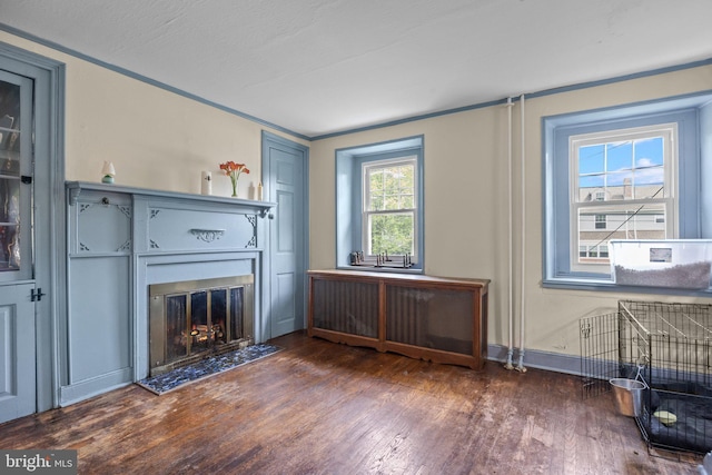unfurnished living room with wood finished floors, a glass covered fireplace, baseboards, and ornamental molding