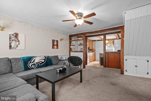 carpeted living room featuring ceiling fan and wood walls