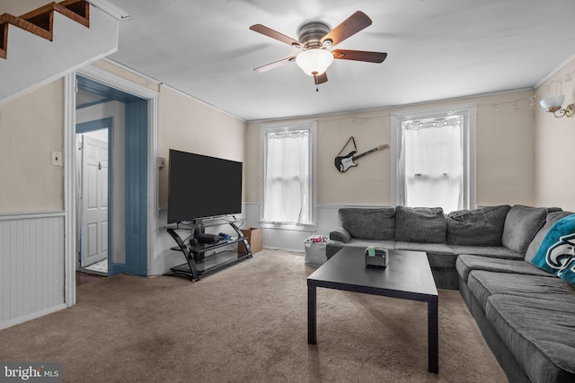 carpeted living room featuring ceiling fan, wainscoting, and crown molding