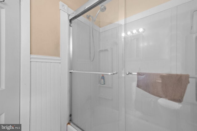 bathroom featuring a shower stall and a wainscoted wall