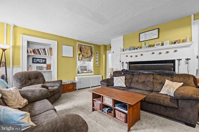 living room with radiator heating unit, carpet flooring, and a fireplace