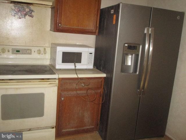 9410 Chippenham Dr, Laurel, MD 20723 - kitchen with white appliances, brown cabinetry, light countertops, and extractor fan