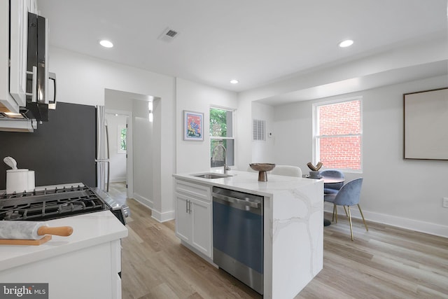 1456 Congress Pl SE, Washington, DC 20020 - kitchen featuring stainless steel appliances, a sink, light stone counters, light wood-style floors, and a kitchen island with sink