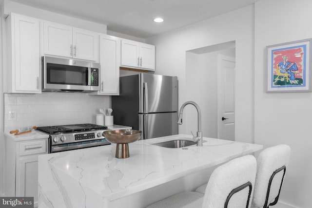 1456 Congress Pl SE, Washington, DC 20020 - kitchen with appliances with stainless steel finishes, a sink, white cabinets, light stone countertops, and backsplash