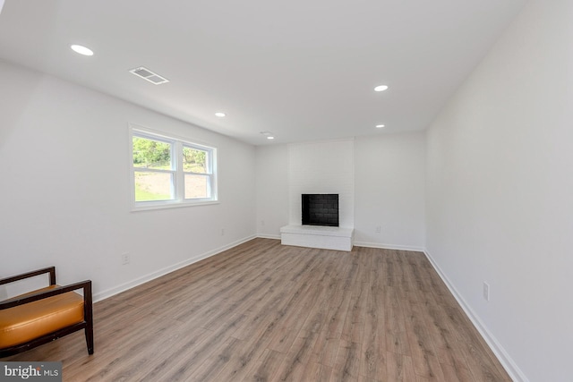 8601 Fort Dr, Manassas, VA 20110 - unfurnished living room with light wood-type flooring, a brick fireplace, recessed lighting, and baseboards