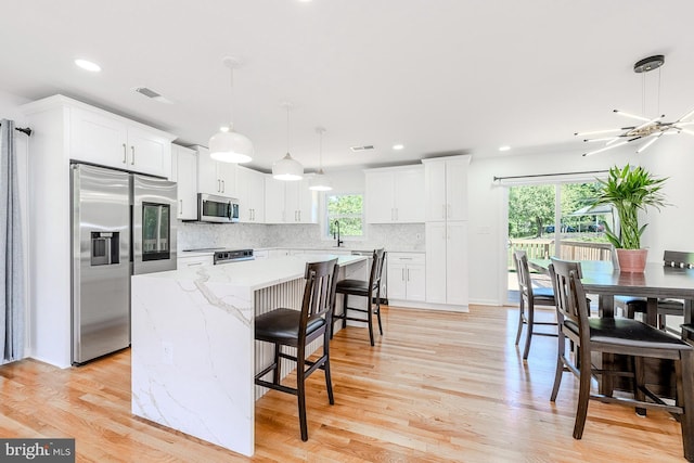 8601 Fort Dr, Manassas, VA 20110 - kitchen with stainless steel appliances, a kitchen island, recessed lighting, backsplash, and white cabinetry