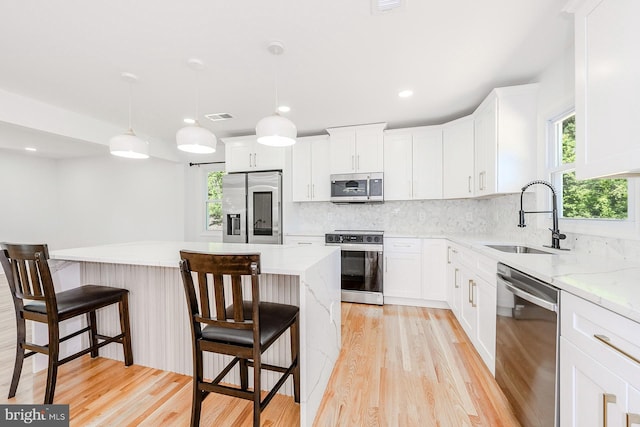 8601 Fort Dr, Manassas, VA 20110 - kitchen with appliances with stainless steel finishes, a sink, light wood-style flooring, a kitchen island, and a breakfast bar