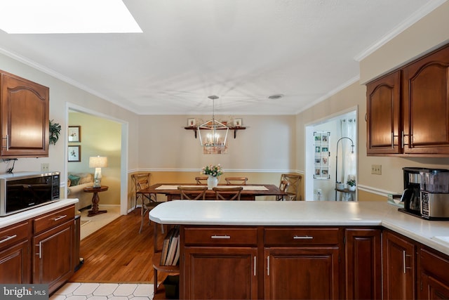 14600 Barton Blvd SW, Cresaptown, MD 21502 - kitchen with a peninsula, light countertops, decorative light fixtures, crown molding, and light wood-type flooring