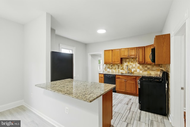 1208 Larchmont Ave, Capitol Heights, MD 20743 - kitchen featuring black appliances, a sink, light stone countertops, brown cabinets, and decorative backsplash