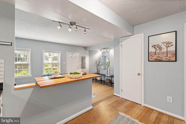 122 N Bedford St Unit A, Arlington, VA 22201 - kitchen with light wood-style flooring, butcher block counters, a textured ceiling, baseboards, and rail lighting