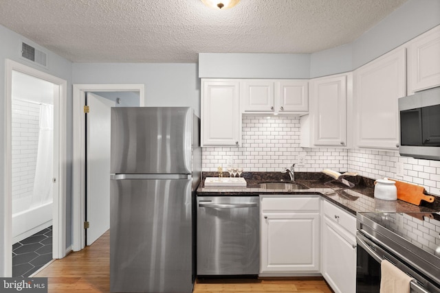 122 N Bedford St Unit A, Arlington, VA 22201 - kitchen with stainless steel appliances, a sink, white cabinets, backsplash, and a textured ceiling