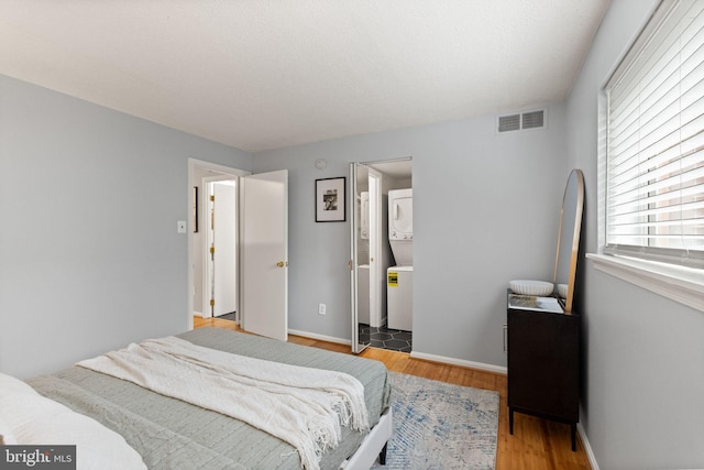 122 N Bedford St Unit A, Arlington, VA 22201 - bedroom with stacked washer / dryer, wood finished floors, baseboards, and ensuite bathroom