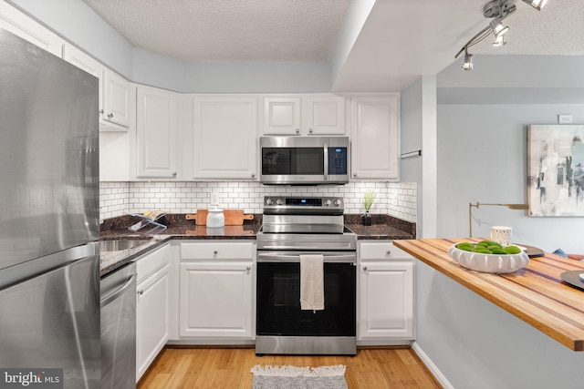 122 N Bedford St Unit A, Arlington, VA 22201 - kitchen with stainless steel appliances, white cabinets, light wood finished floors, and a textured ceiling