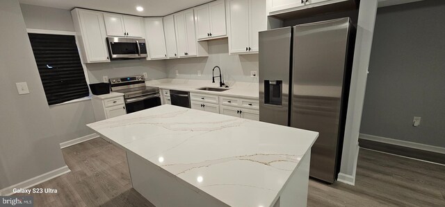 5303 55th Pl, Riverdale, MD 20737 - kitchen featuring stainless steel appliances, a sink, wood finished floors, baseboards, and white cabinetry