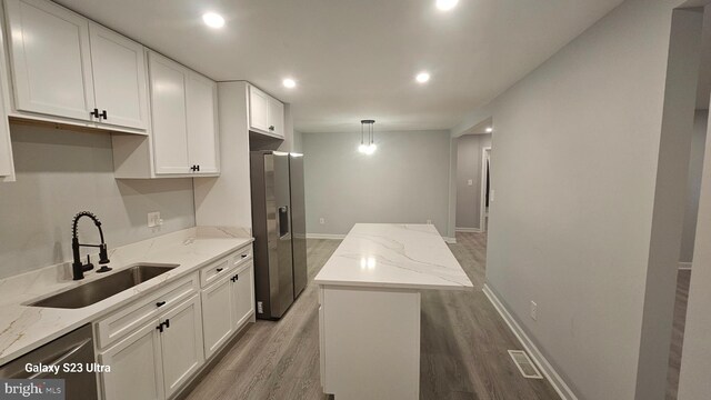 5303 55th Pl, Riverdale, MD 20737 - kitchen featuring a sink, light wood finished floors, appliances with stainless steel finishes, a center island, and white cabinetry