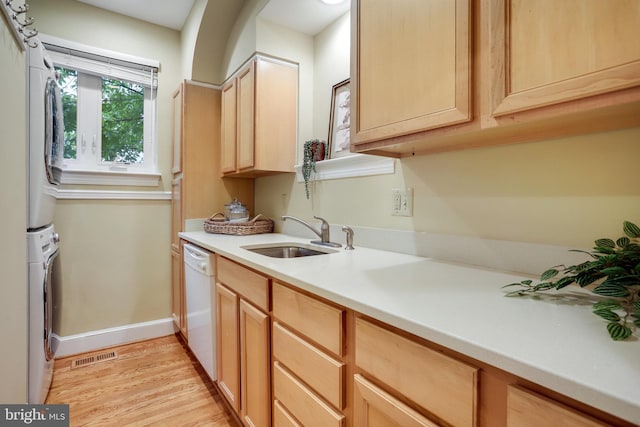 2739 Chesapeake St NW, Washington, DC 20008 - kitchen featuring stacked washer / dryer, a sink, white dishwasher, baseboards, and light countertops