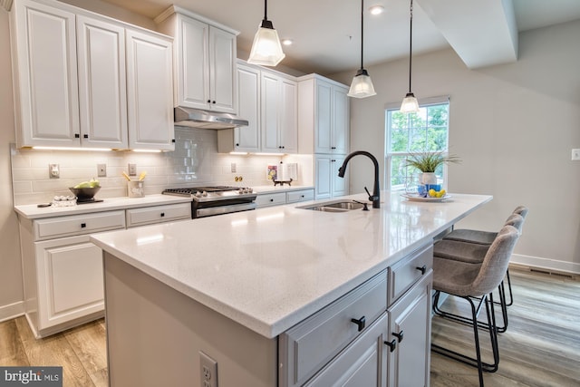 3163 Dodder Way, Odenton, MD 21113 - kitchen featuring gas stove, a sink, under cabinet range hood, an island with sink, and light wood-type flooring