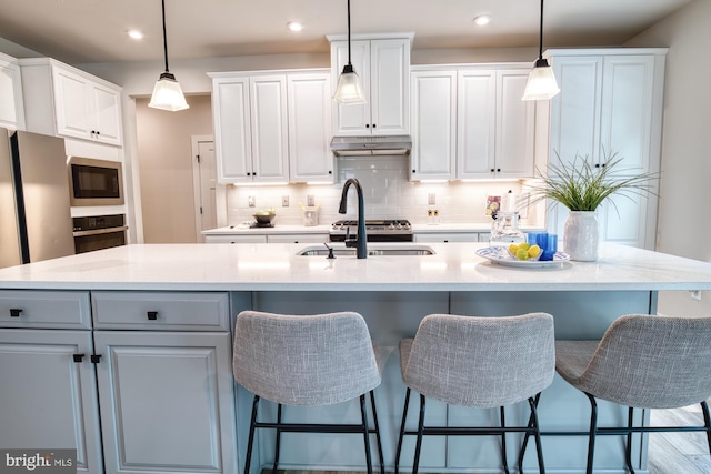 3163 Dodder Way, Odenton, MD 21113 - kitchen with stainless steel oven, under cabinet range hood, white cabinets, decorative backsplash, and hanging light fixtures