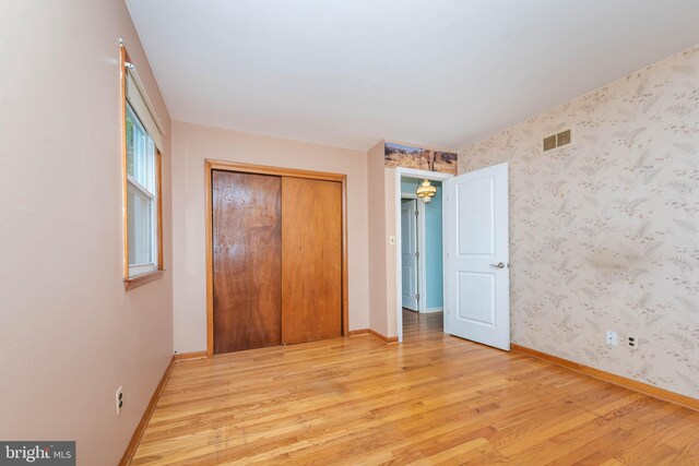 611 N Ct, Linthicum Heights, MD 21090 - unfurnished bedroom featuring light wood-style floors, wallpapered walls, baseboards, and a closet