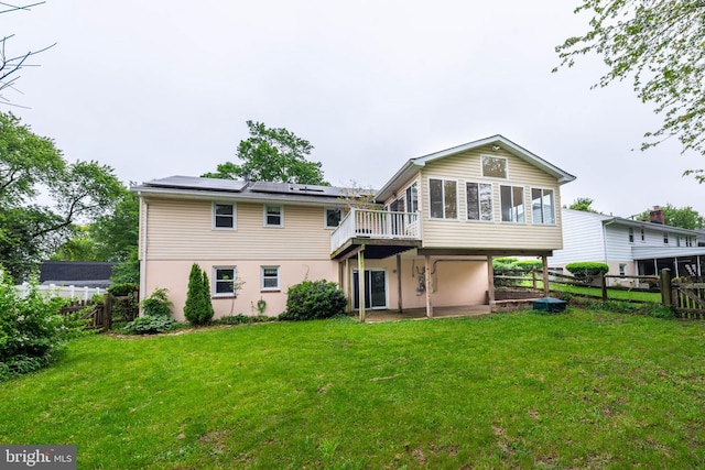 611 N Ct, Linthicum Heights, MD 21090 - rear view of house with a sunroom, roof mounted solar panels, stucco siding, and a wooden deck