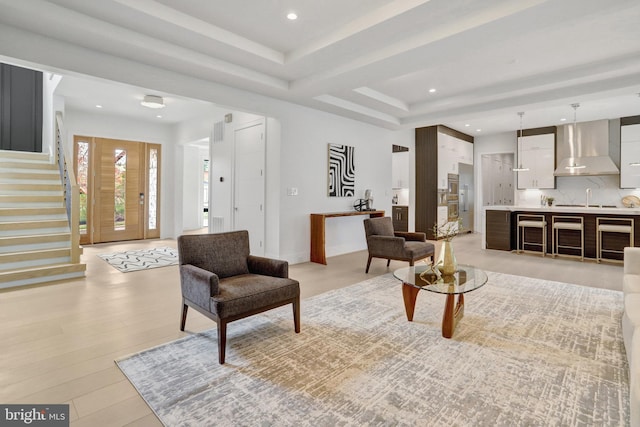 living room with stairs, recessed lighting, light wood finished floors, and a tray ceiling