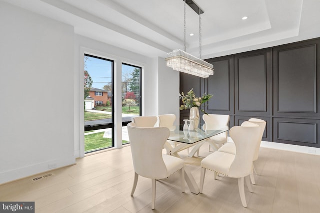dining area with a raised ceiling, a chandelier, recessed lighting, and light wood-type flooring